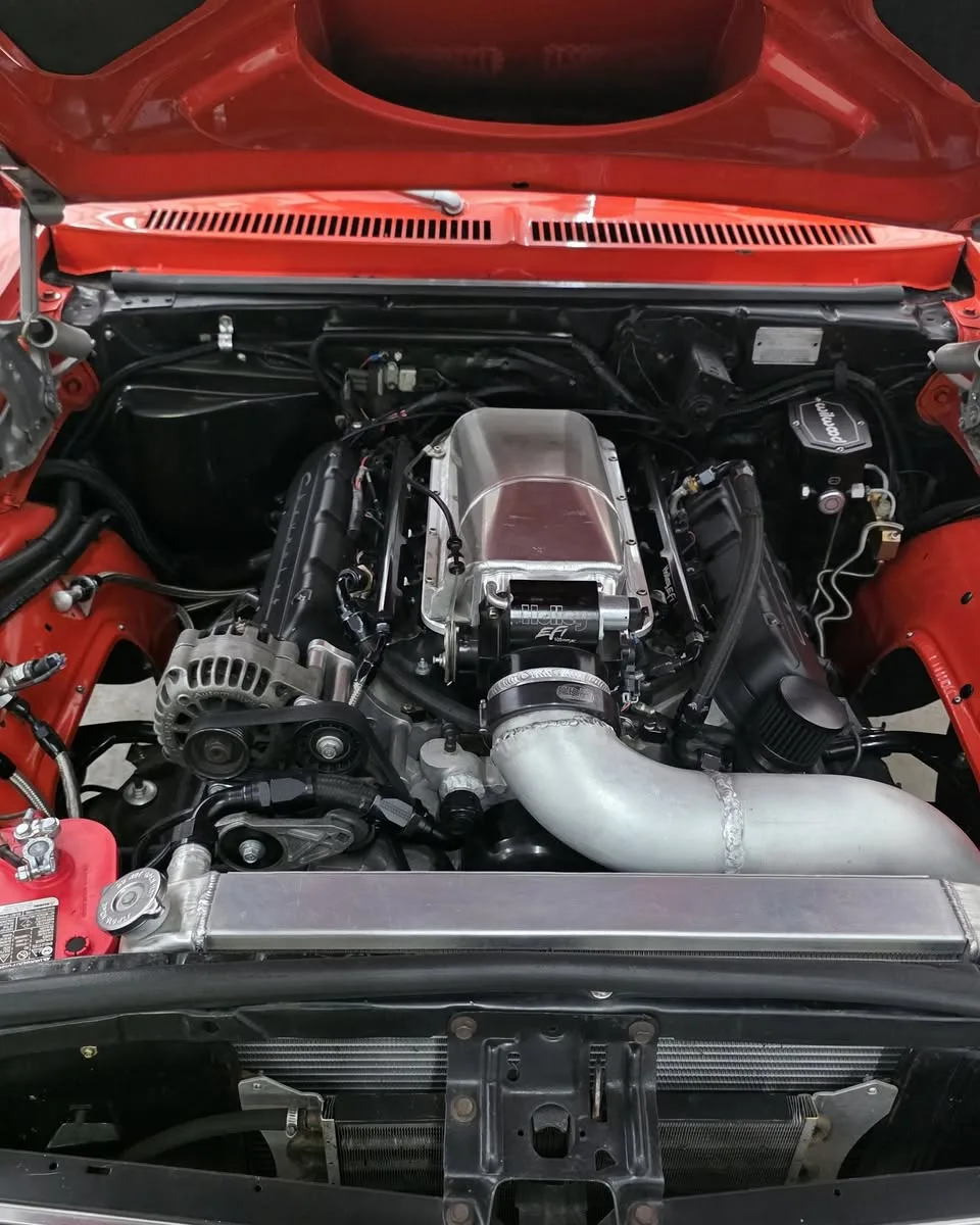 A supercharged V8 in the engine bay of a red car